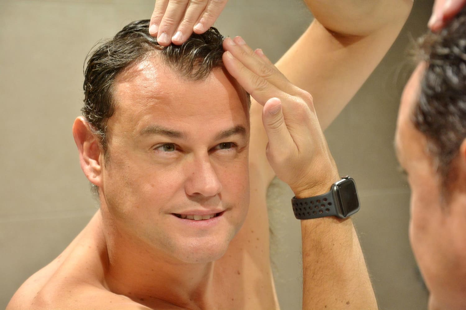 Man checking his receding hairline in mirror.